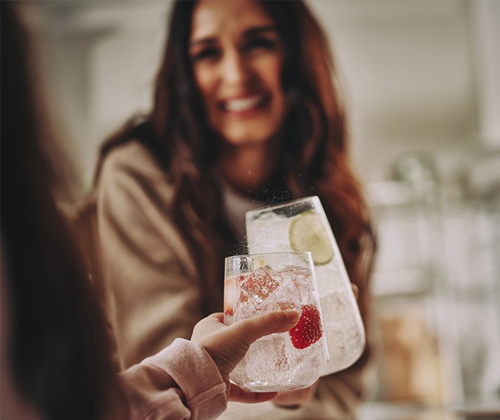 Mama stukająca się szklanką z wodą gazowaną SodaStream z córką - zdjęcie